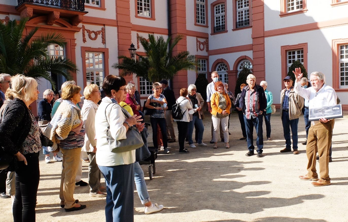 Bei strahlendem Sonnenschein genießen die Ausflügler die Erklärungen des Gästeführers im Schlossgarten Biebrich